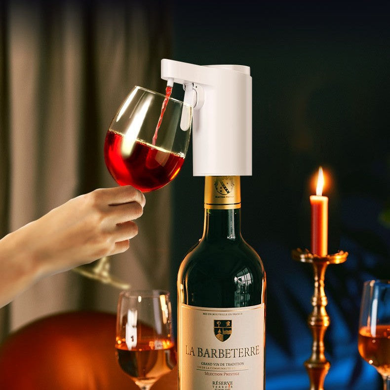Dispensador automático de vino blanco sirviendo una copa en una mesa con una botella de vino tinto, copas adicionales y una vela encendida en un ambiente de cena.