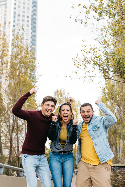 3 amigos felices gritando y sonriendo en un parque de una ciudad